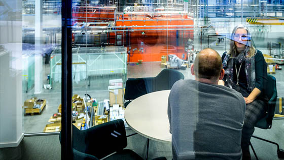A photo of two people having a conversation in front of the beamlines