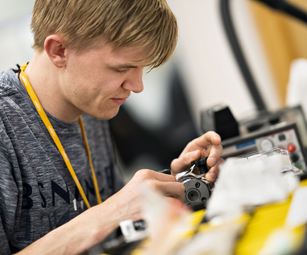 Young male scientist at MAX IV studying detailed machinery in hands.