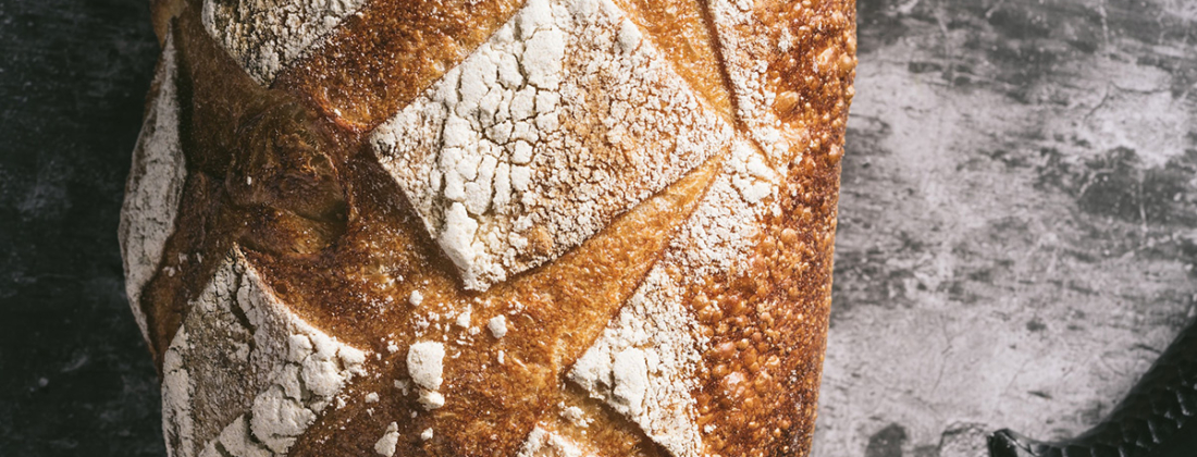 Close up image of freshly baked sourdough bread loaf on black and white background