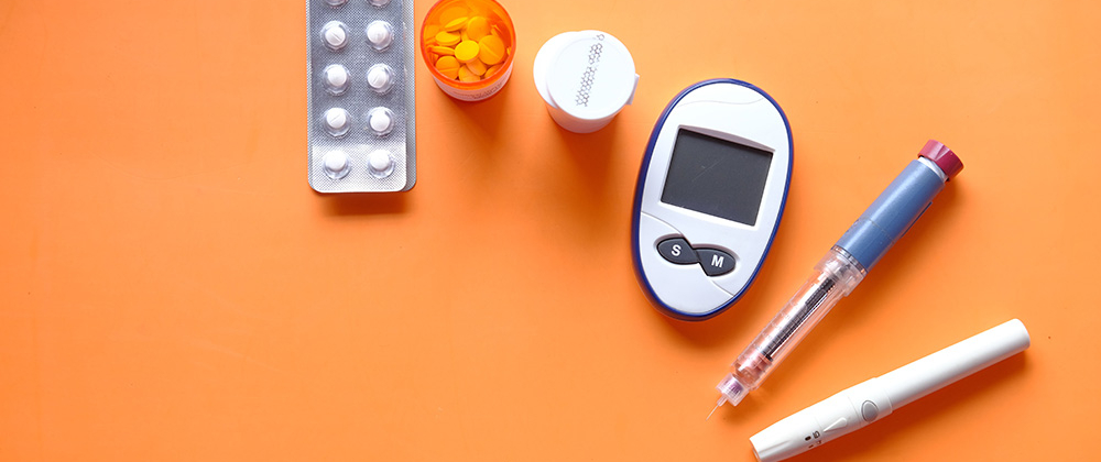 diabetes device for measuring blood sugar levelsand tablets on orange background