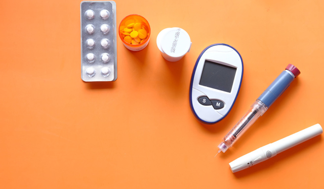 diabetes device for measuring blood sugar levelsand tablets on orange background