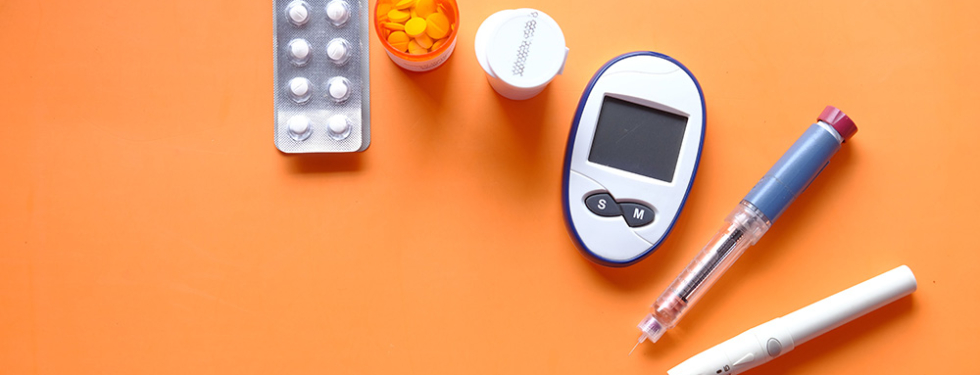 diabetes device for measuring blood sugar levelsand tablets on orange background