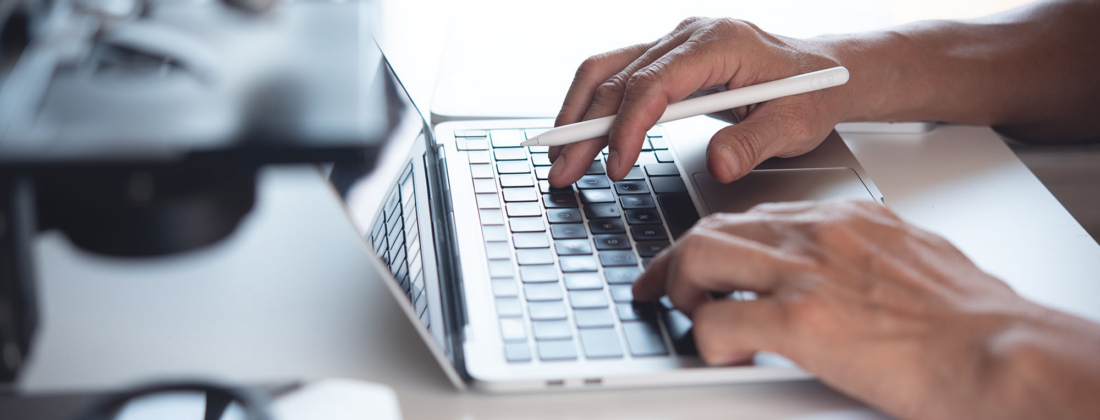 Scientist working on laptop computer and using digital tablet wi