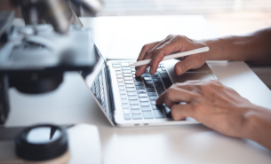 Scientist working on laptop computer and using digital tablet wi