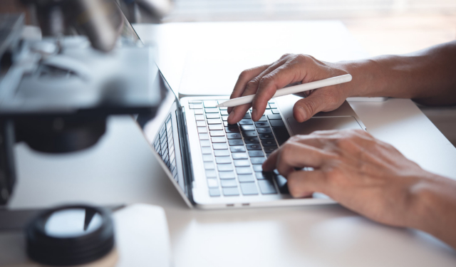 Scientist working on laptop computer and using digital tablet wi